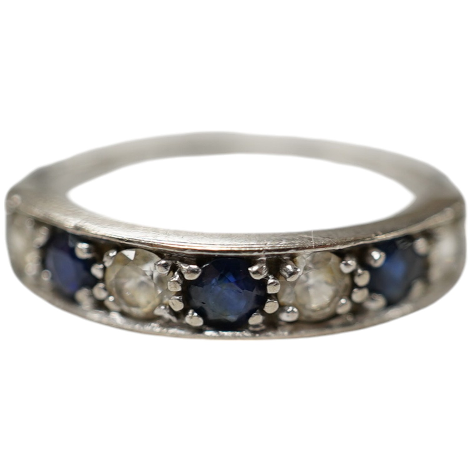 A 1970's 18ct white gold, sapphire and simulated diamond set half hoop ring, size O, gross weight 3.5 grams. Condition - fair